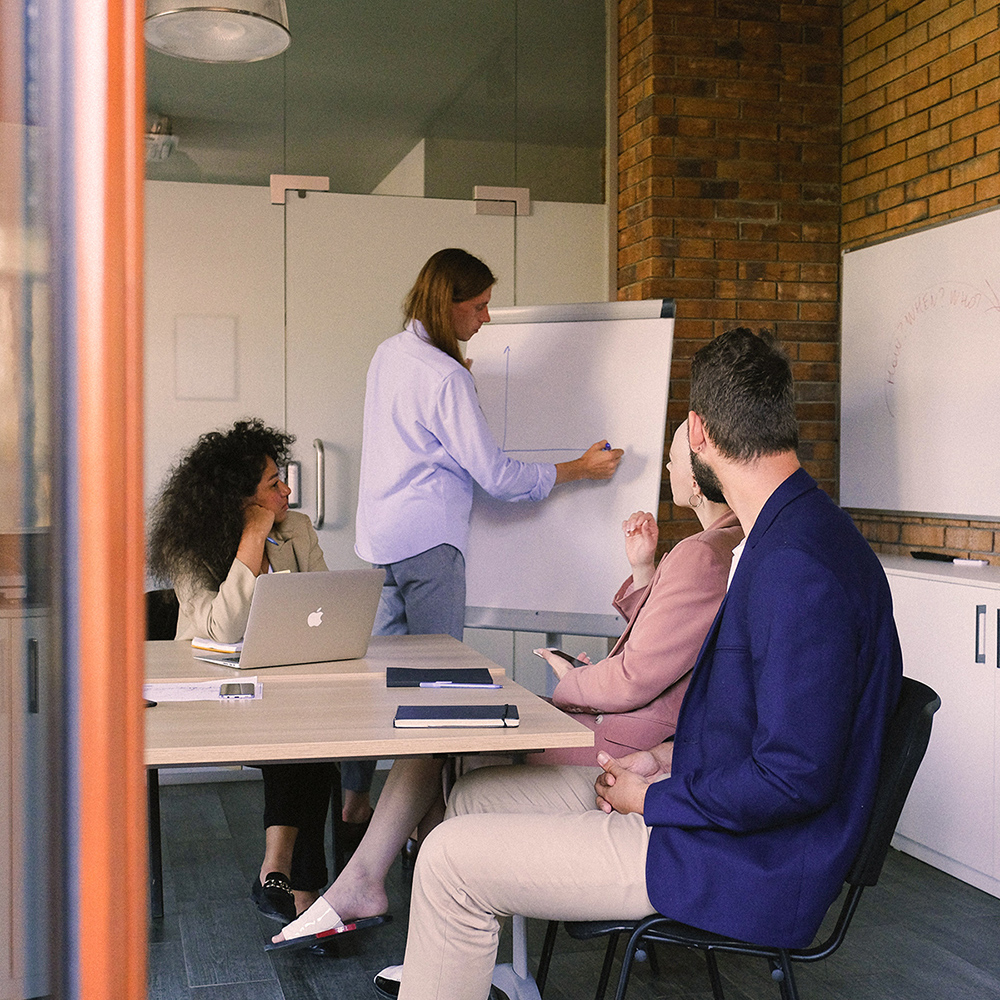 Group of people in a meeting with a Mac on the desk