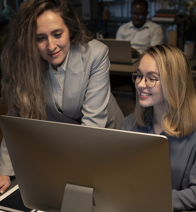 Two women in an office looking at an iMac