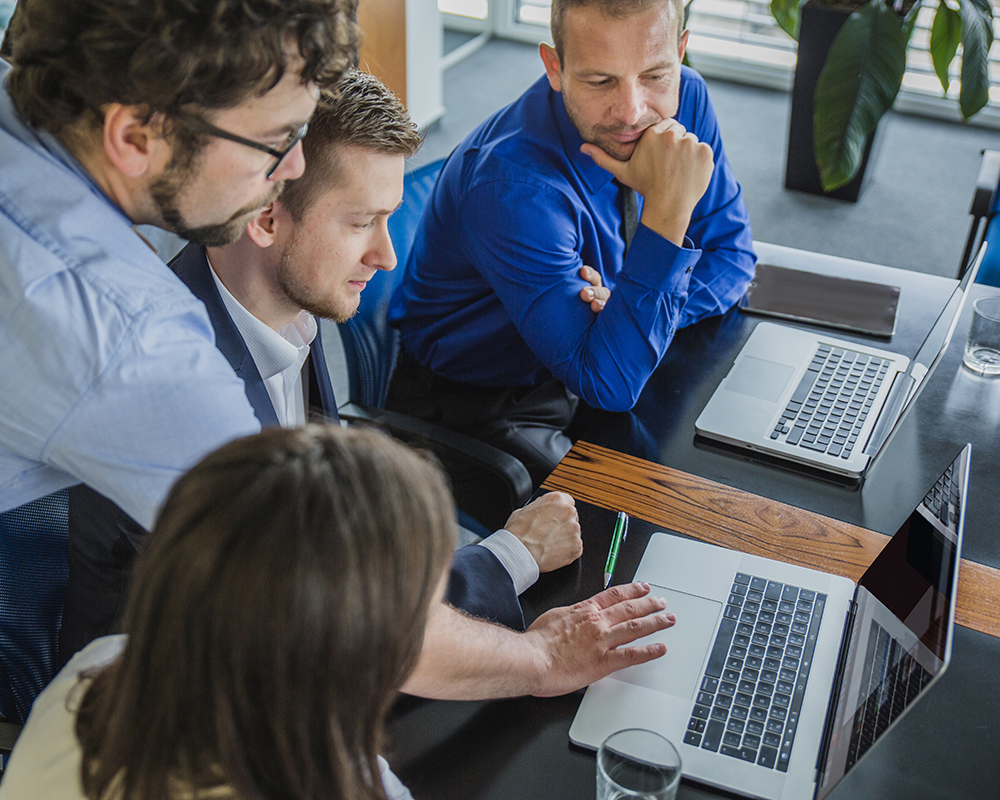 Group of people checking work on a MacBook computer