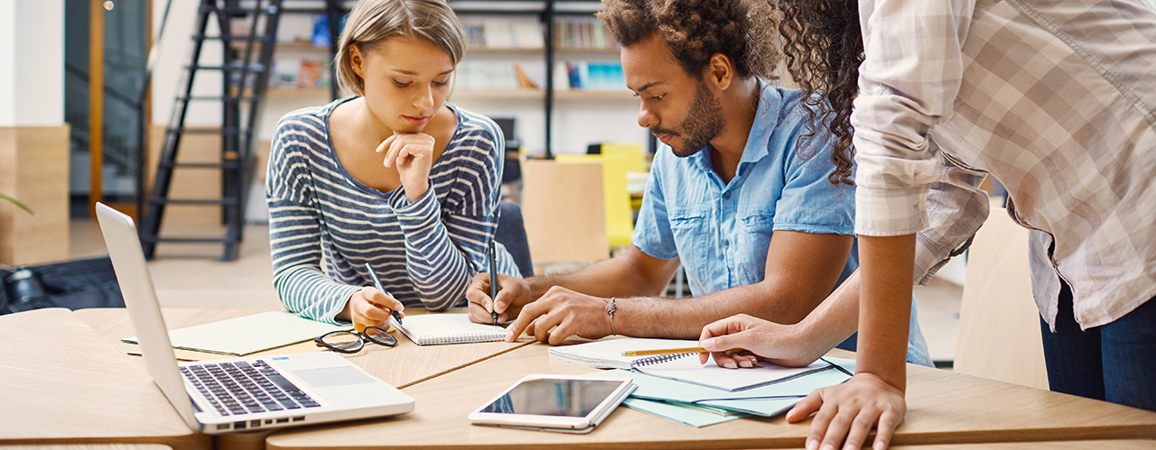 Group of people working on a project with an iPad and a Mac computer on the desk