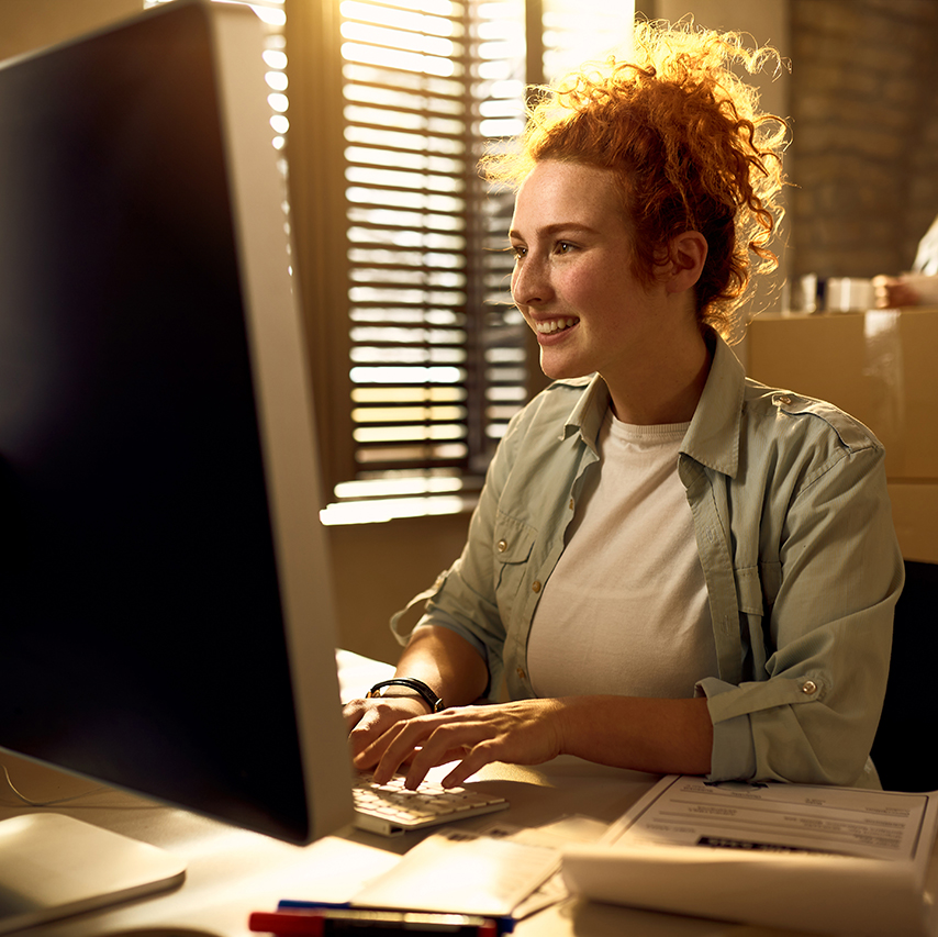 Happy woman using her Mac computer to write an email