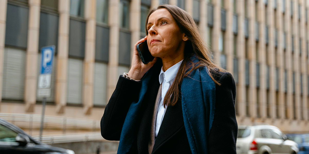 Business woman walking on the street while taking a call on her iPhone